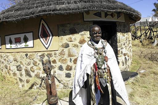 Vusamazulu Credo Mutwa in front of his traditional Ndebele hut at the cultural village